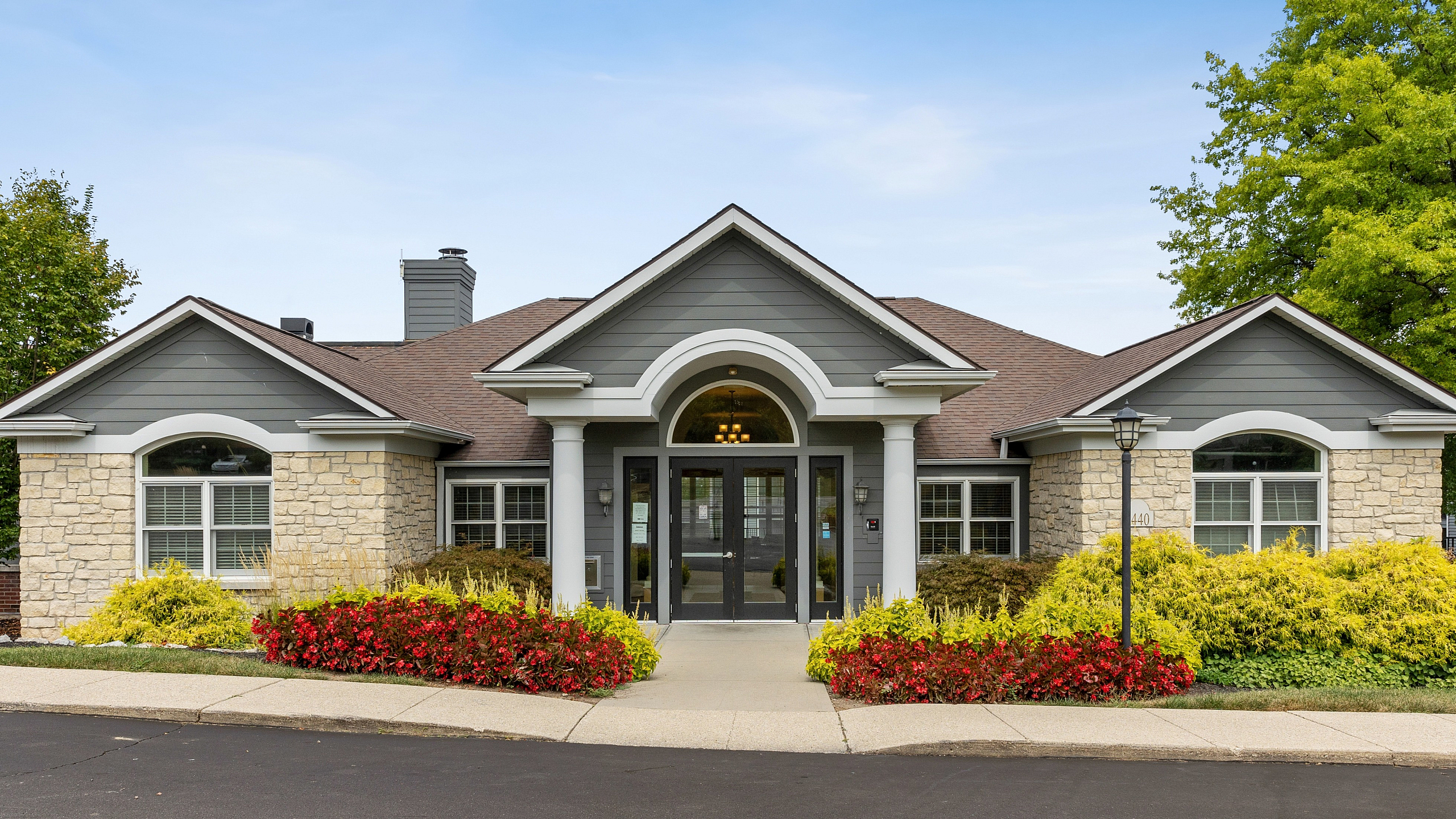 Elegant suburban home with stone facade and manicured landscaping under a clear blue sky.
