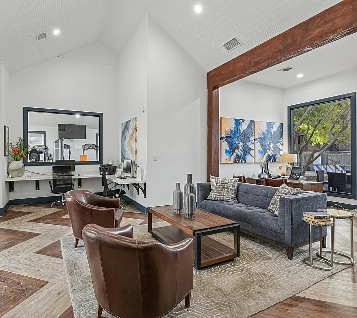 Chic open-concept living area with modern decor, featuring cozy seating, stylish artwork, and a sleek workspace, perfect for relaxation or productivity.