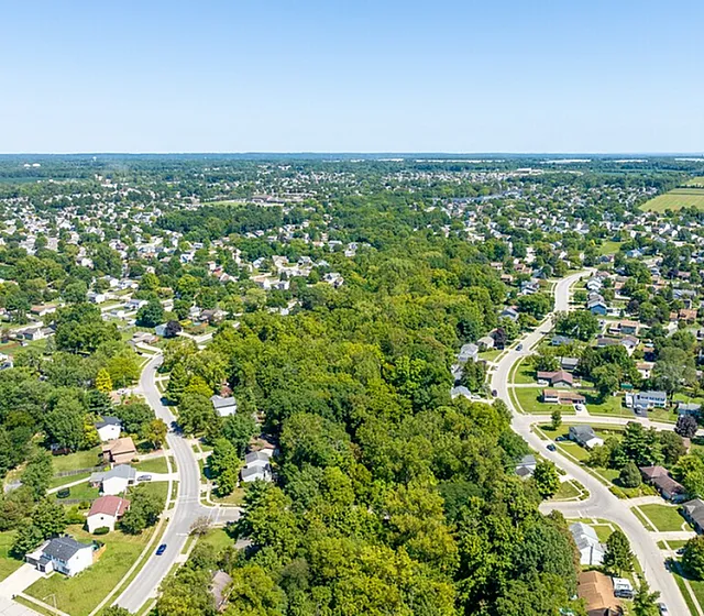 Captivating aerial view showcasing a lush, green neighborhood with winding streets and charming homes, enveloped by abundant nature.