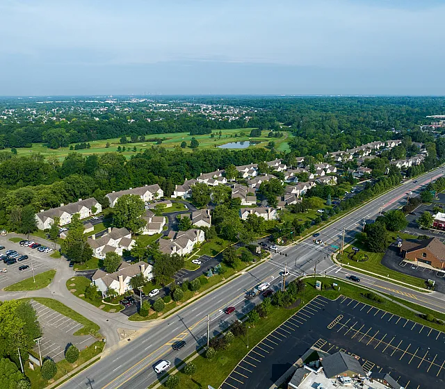 Aerial view of charming residential neighborhood surrounded by lush greenery, featuring well-planned houses and ample parking spaces, showcasing a serene community atmosphere.
