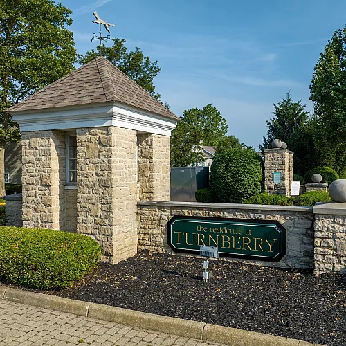 Inviting stone entrance to The Residences at Turnberry with well-maintained landscaping and elegant signage.