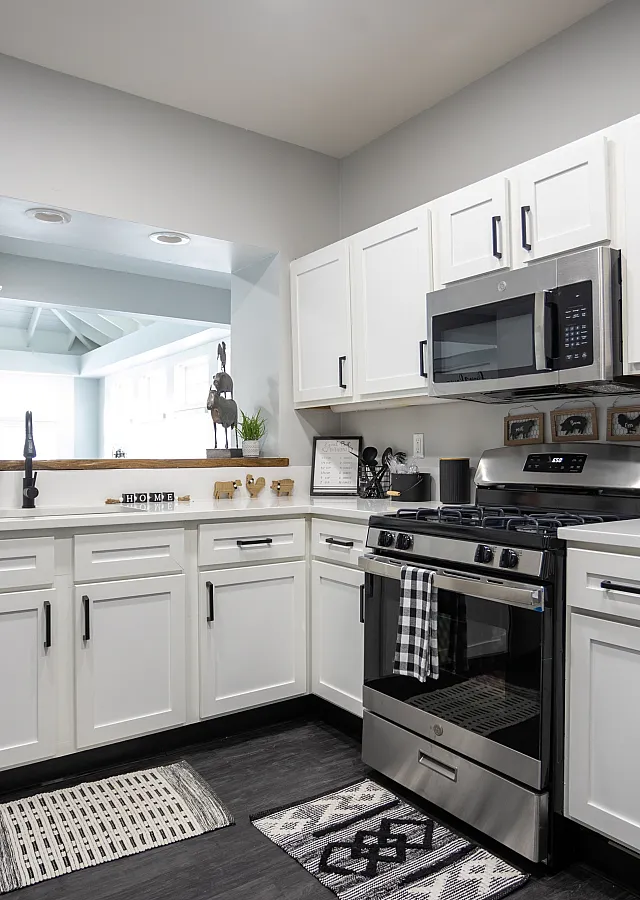 Modern farmhouse-style kitchen with sleek stainless steel appliances, white cabinetry, and rustic decorative accents.
