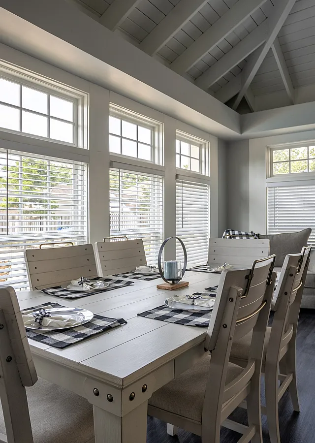 Modern dining room bathed in natural light with vaulted ceilings and chic decor, featuring elegant table settings and a cozy seating area.