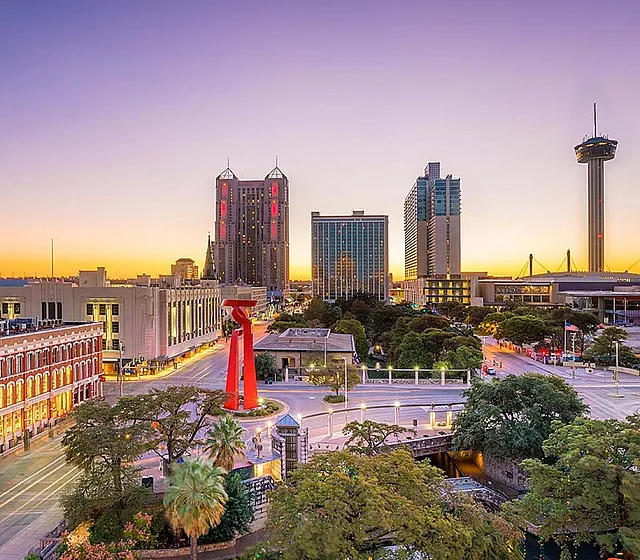 Vibrant city skyline at sunset showcasing towering buildings and lush greenery.