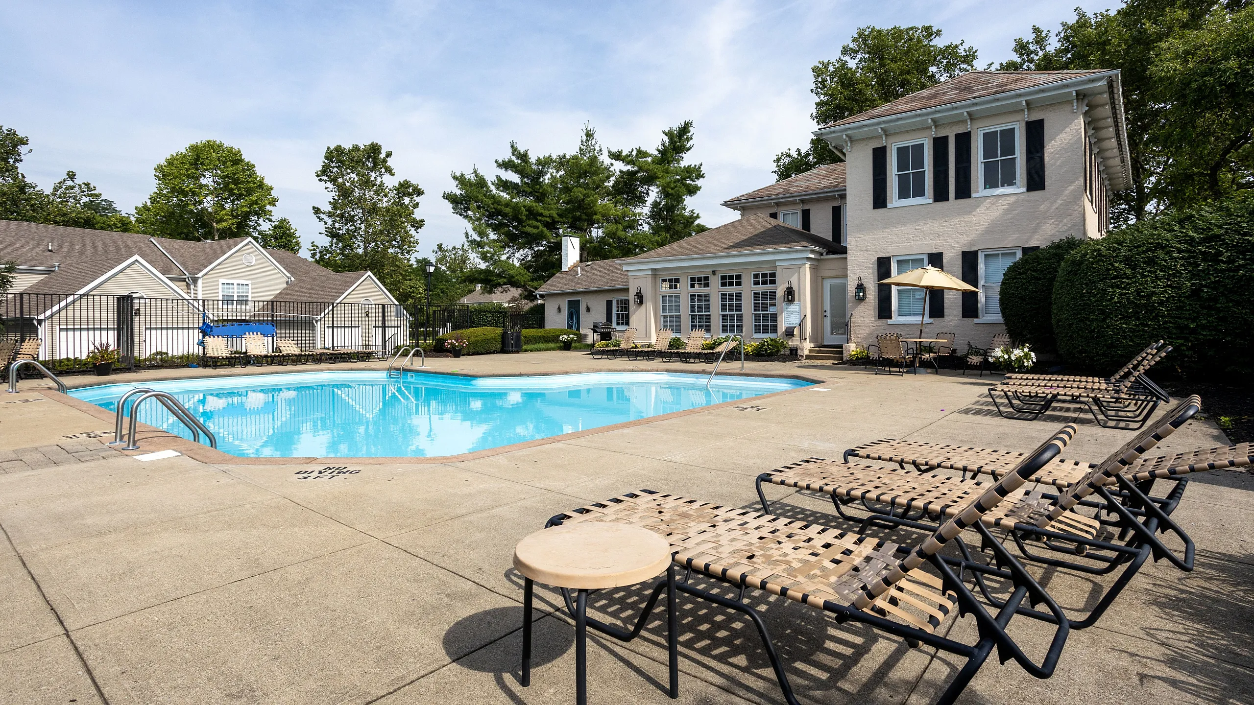 Charming apartment community with a pristine swimming pool, surrounded by relaxing sun loungers and lush greenery, perfect for leisure and outdoor enjoyment.