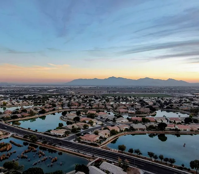 Breathtaking sunset view over a serene suburban neighborhood with tranquil lakes and distant mountains.