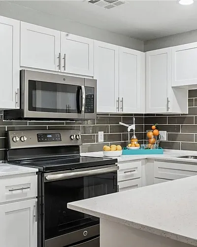Modern kitchen with sleek white cabinetry, stainless steel appliances, and elegant gray subway tile backsplash.