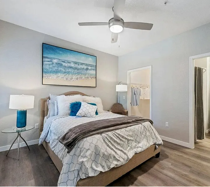 Inviting bedroom retreat with coastal artwork, elegant lighting, and attached modern bathroom.