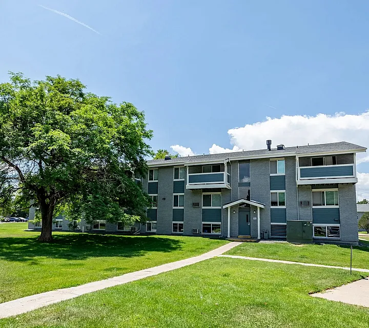 Charming apartment building surrounded by lush greenery and open space, perfect for serene living.