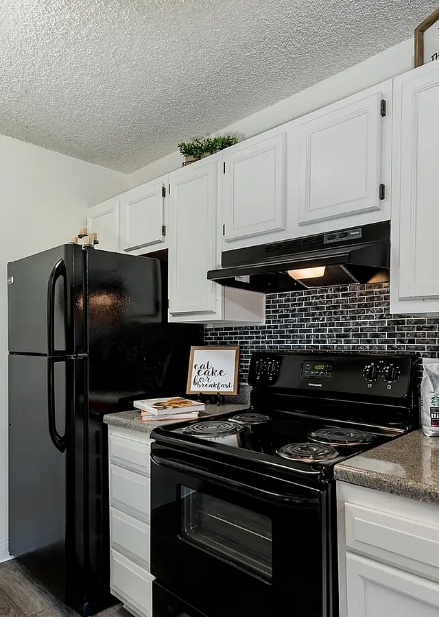 Charming kitchen with modern black appliances, elegant white cabinetry, and stylish backsplash. Cozy and inviting cooking space for gourmet meals.