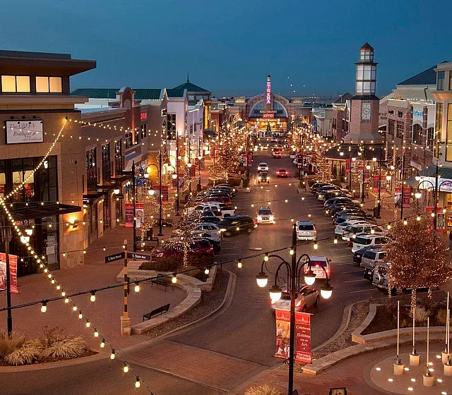 Vibrant urban street scene at night with twinkling string lights, bustling shops, and lively atmosphere.