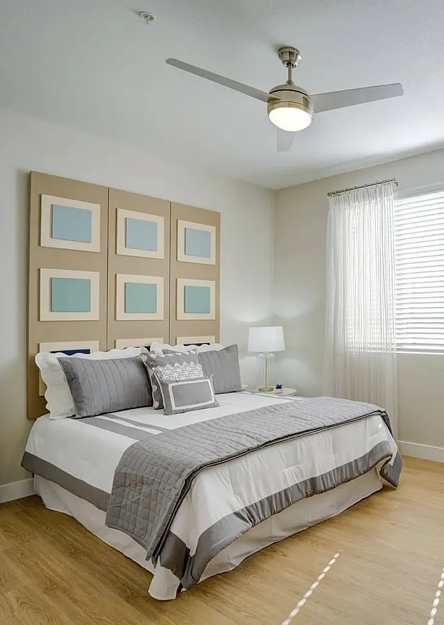 Inviting bedroom with modern decor, elegant wooden flooring, and abundant natural light through sheer curtains.