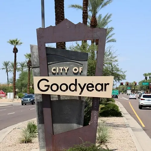 Vibrant city sign for Goodyear, Arizona, surrounded by lush palm trees and a bustling roadway, showcasing a thriving community atmosphere.