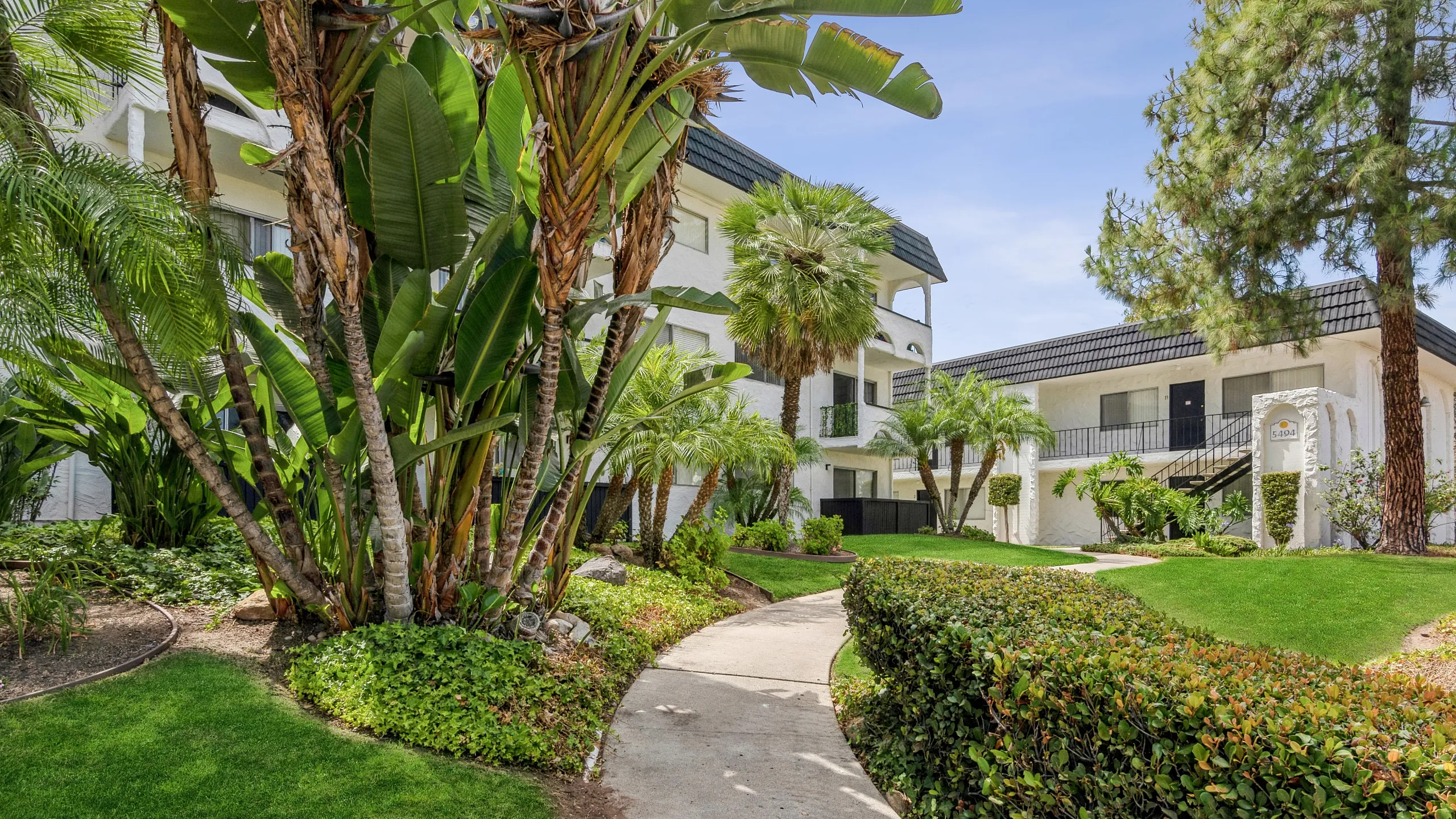 Charming apartment complex surrounded by lush greenery and palm trees, offering a picturesque and serene living environment.