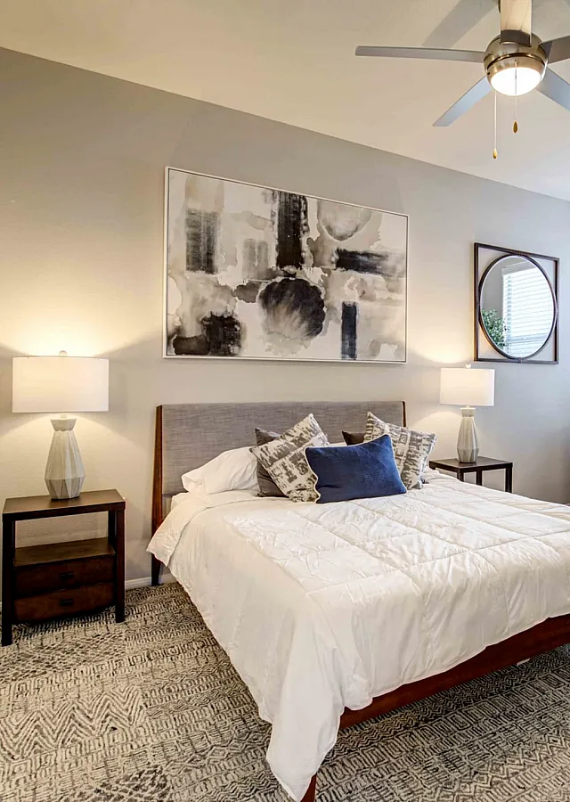 Cozy bedroom with plush carpet, stylish decor, and abundant natural light, perfect for relaxation.