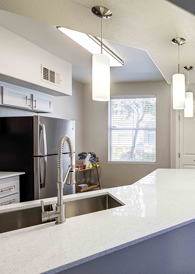 Modern kitchen with sleek white countertops and a stylish dining area with a glass round table, perfect for bright and inviting living.