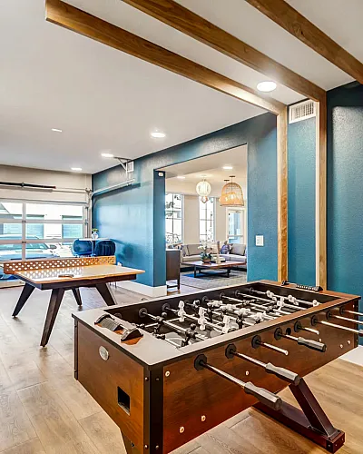 Vibrant game room with foosball and table tennis, featuring modern decor and blue accent wall.