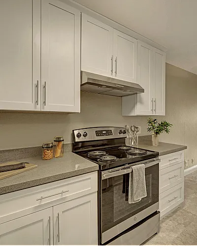 Modern open-concept kitchen and living room with sleek white cabinetry, stainless steel appliances, and elegant ceiling fan, perfect for stylish urban living.