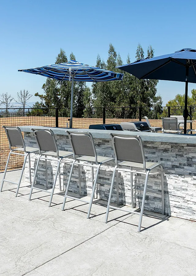 Inviting outdoor patio with chic bar seating and umbrellas, surrounded by scenic open views, perfect for relaxation and entertaining.