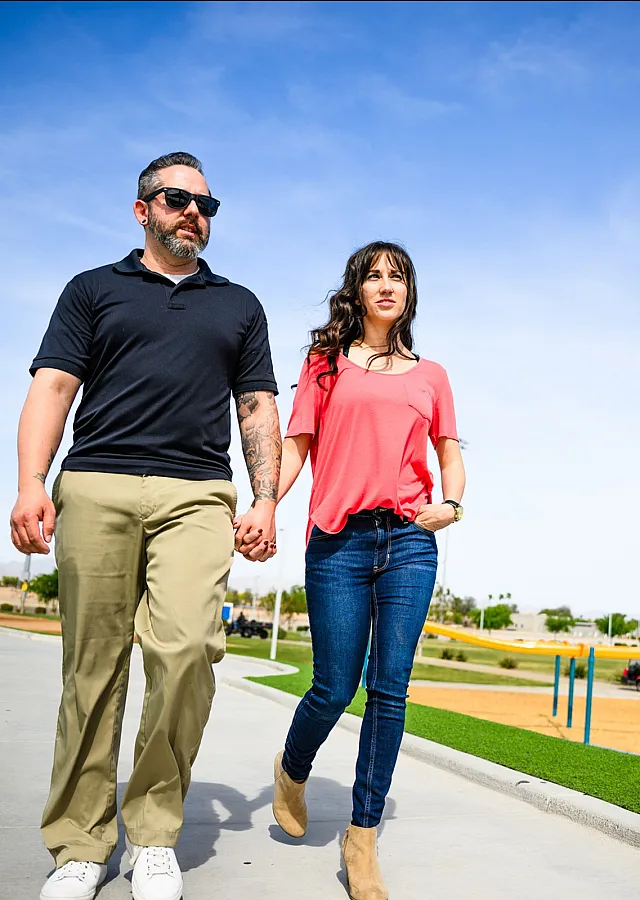 Happy couple enjoying a sunny day at the park with vibrant blue skies and lush green surroundings.