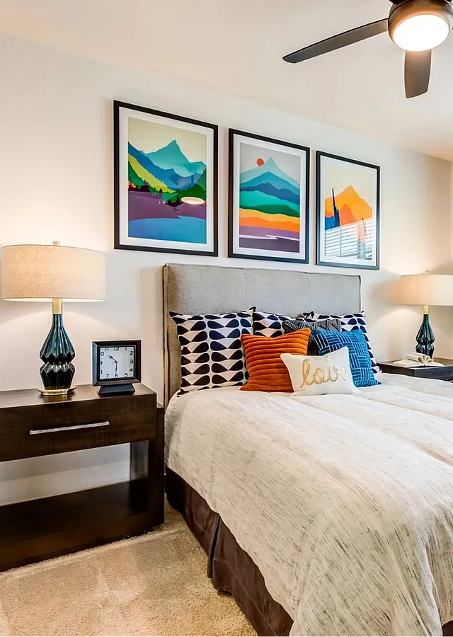 Inviting and modern bedroom showcasing vibrant mountain artwork, plush bedding, and ample natural light from large windows.