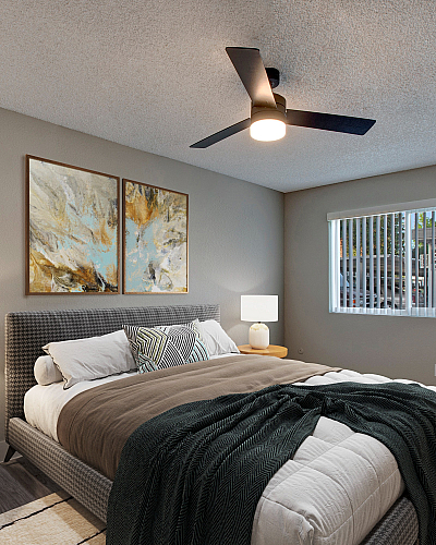 Cozy bedroom with stylish decor, featuring modern ceiling fan, abstract artwork, and ample natural light from large window.