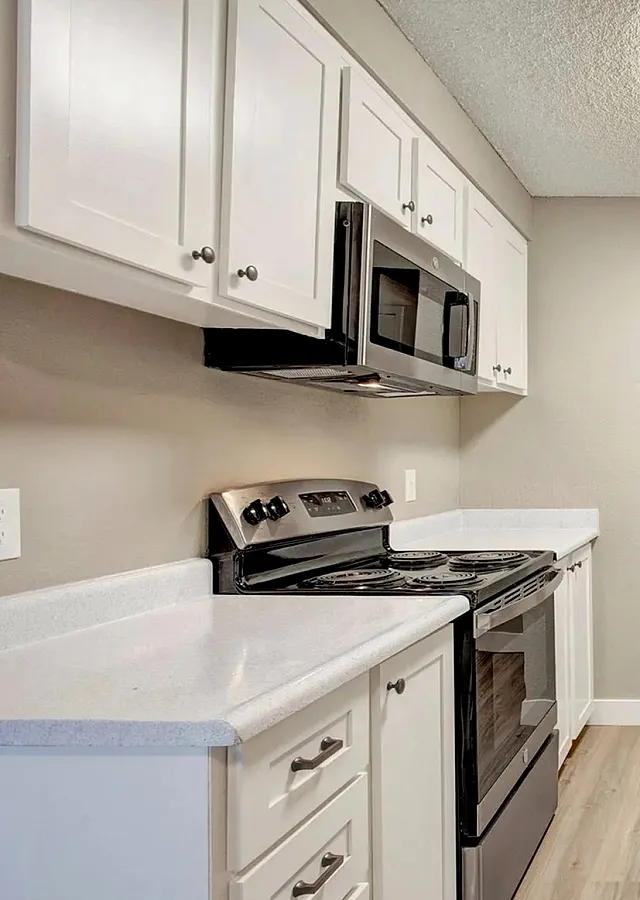 Modern kitchen with sleek stainless steel appliances, white cabinetry, and elegant wood flooring, perfect for culinary enthusiasts.
