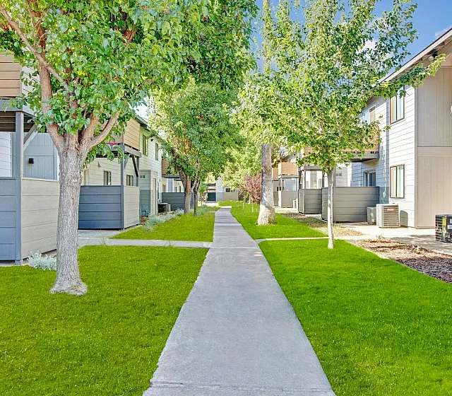 Charming apartment complex with lush green gardens and inviting walkways, offering serene living spaces surrounded by nature.