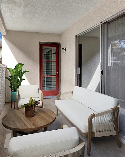 Charming apartment patio with cozy outdoor seating, stylish wooden table, and vibrant potted plants, perfect for relaxing in a sunny urban setting.
