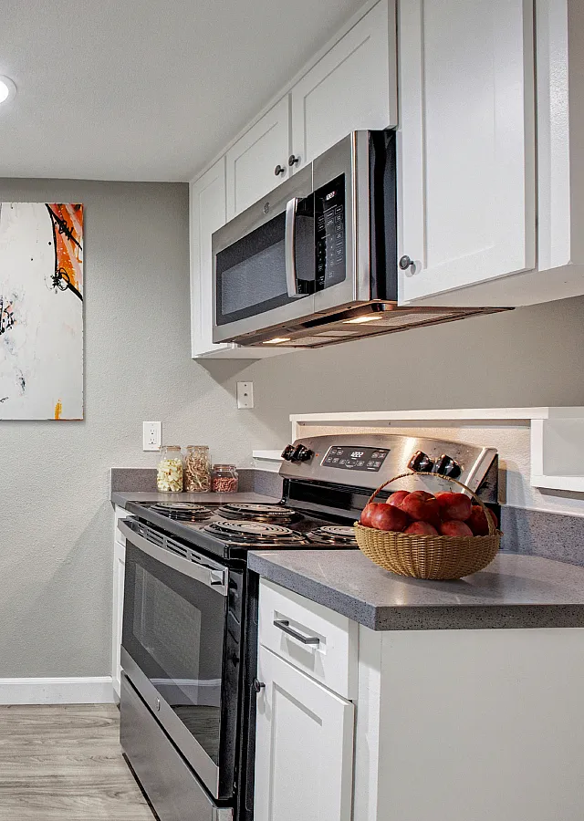 Modern kitchen boasting sleek countertops, stainless steel appliances, and elegant white cabinetry, complemented by stylish artwork.