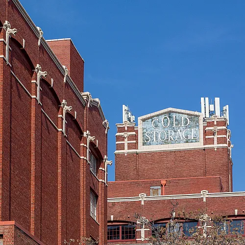 Iconic red brick architecture of a historic cold storage building standing proudly against a vibrant blue sky.