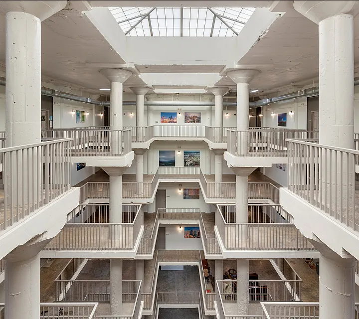 Bright and modern multi-level atrium with sleek railings, large structural columns, and skylight.