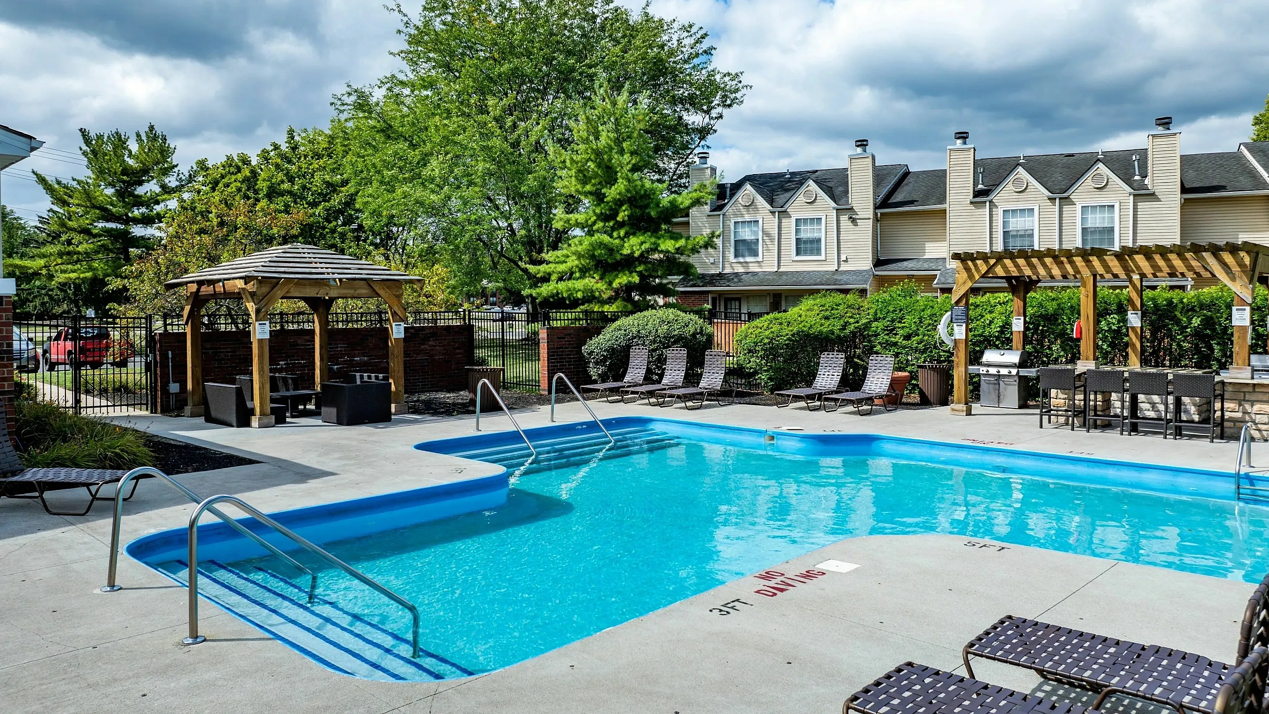 Inviting outdoor pool area with sun loungers, cozy gazebo, and lush greenery, perfect for relaxation and social gatherings.