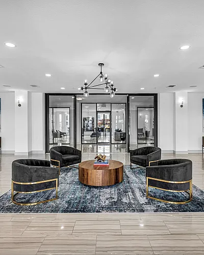Elegant modern lobby with stylish armchairs, a chic geometric chandelier, and sleek marble flooring, creating a luxurious atmosphere.