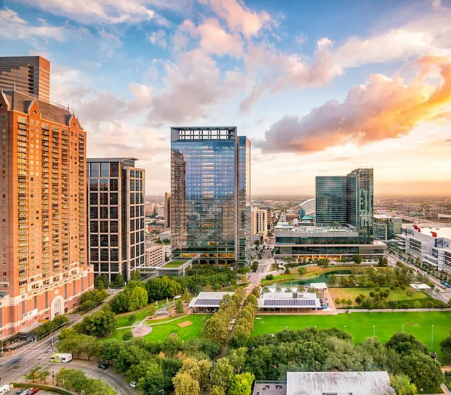 Vibrant cityscape at sunset featuring modern skyscrapers, lush green park, and dynamic urban architecture.