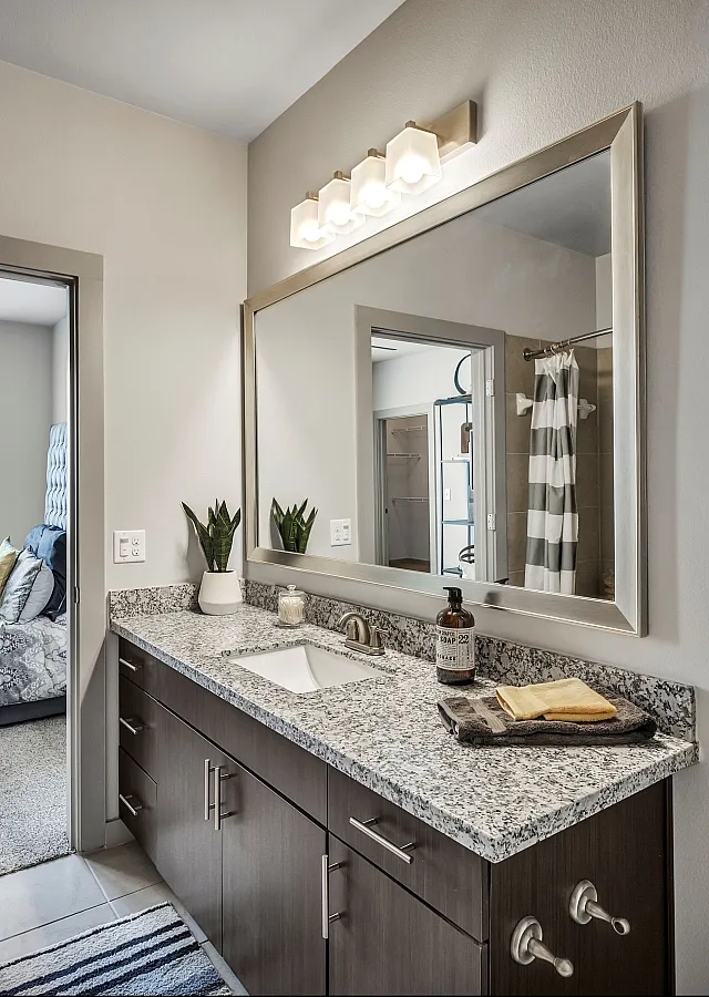 Contemporary bathroom with elegant granite countertop, sleek fixtures, and inviting bedroom view through doorway.