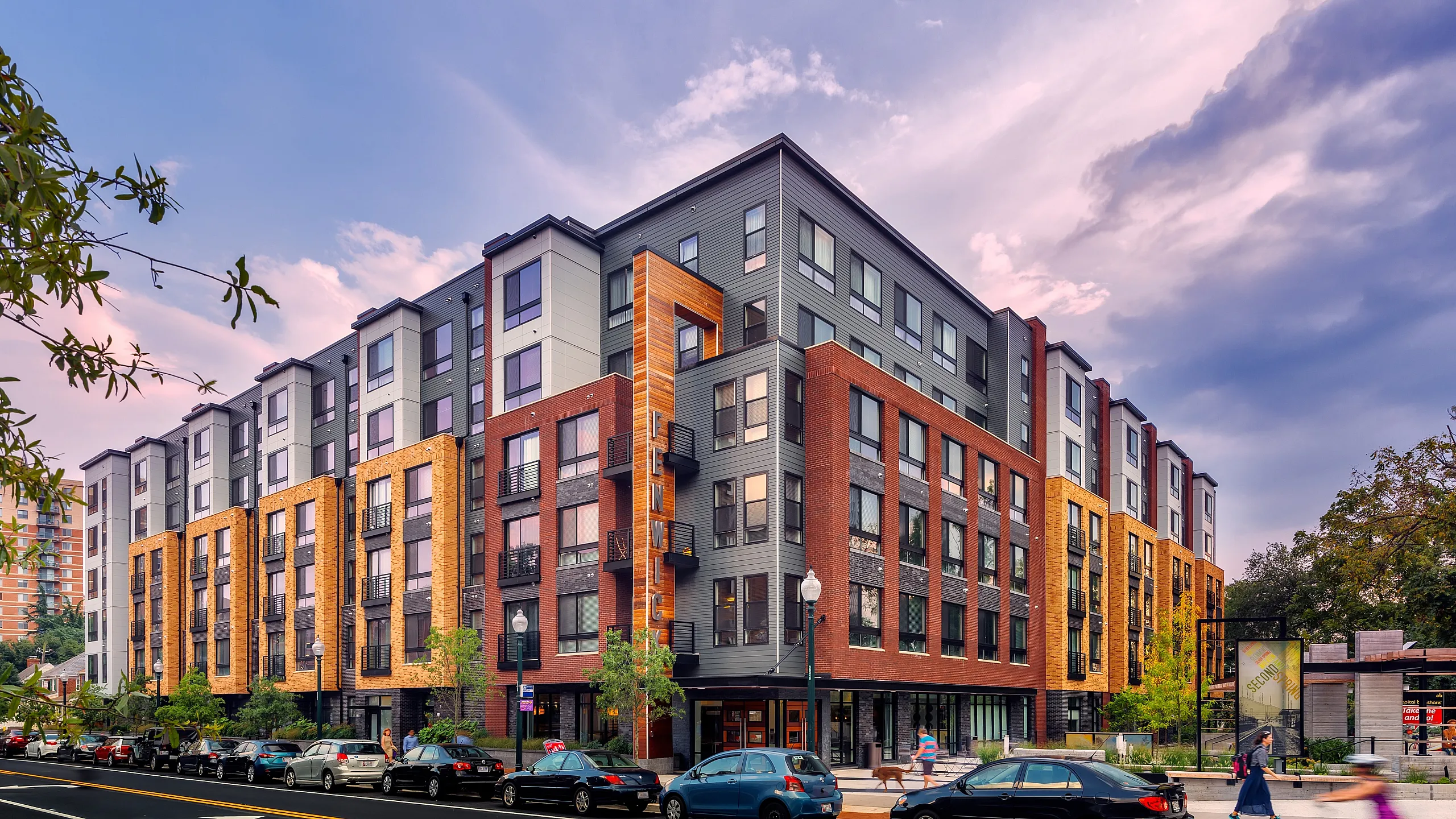 Modern urban apartment complex with vibrant architecture, featuring large windows and a welcoming entrance, perfect for city living.