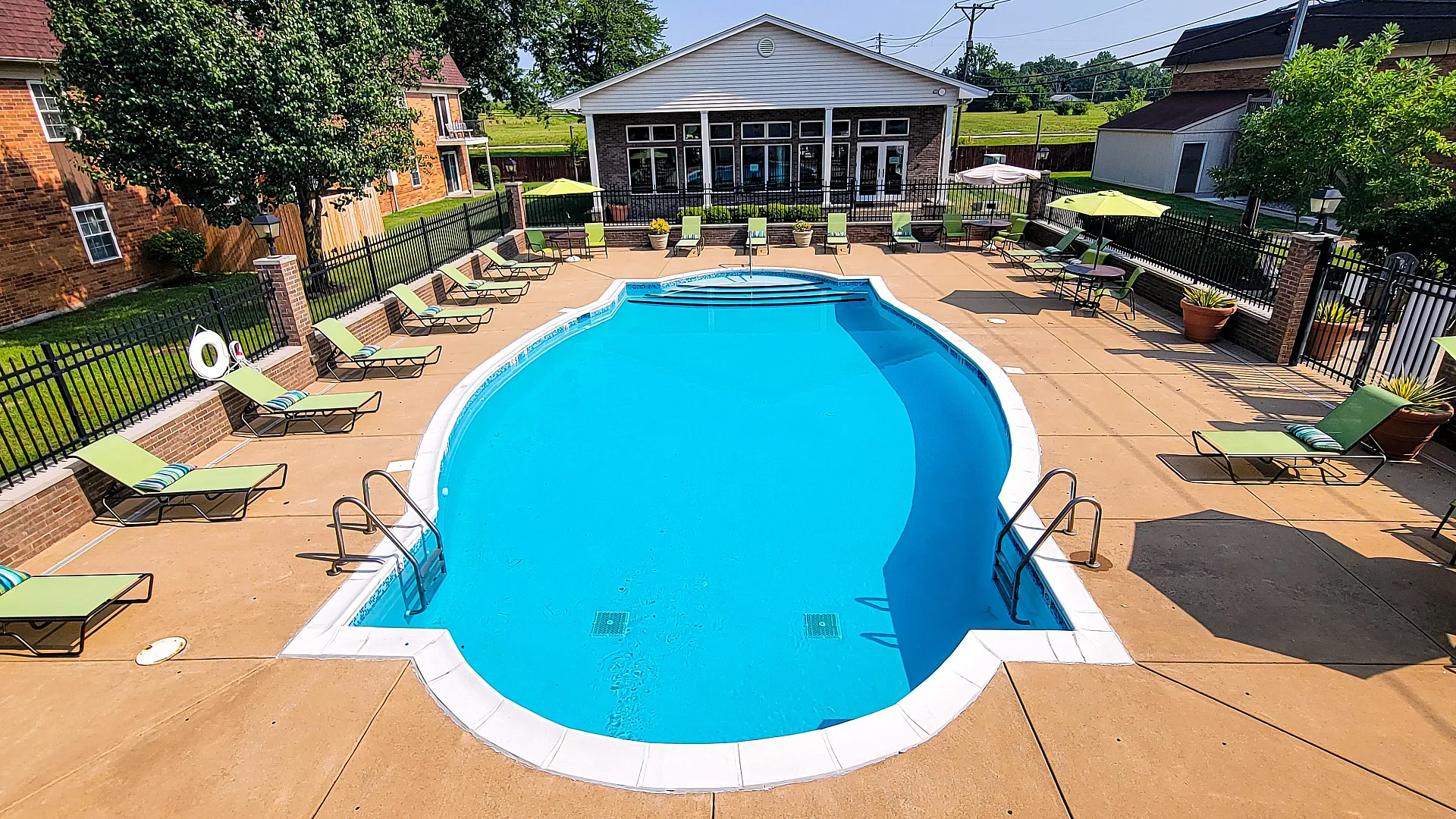 Inviting outdoor pool area with modern lounge chairs and vibrant greenery, offering a perfect summer retreat.