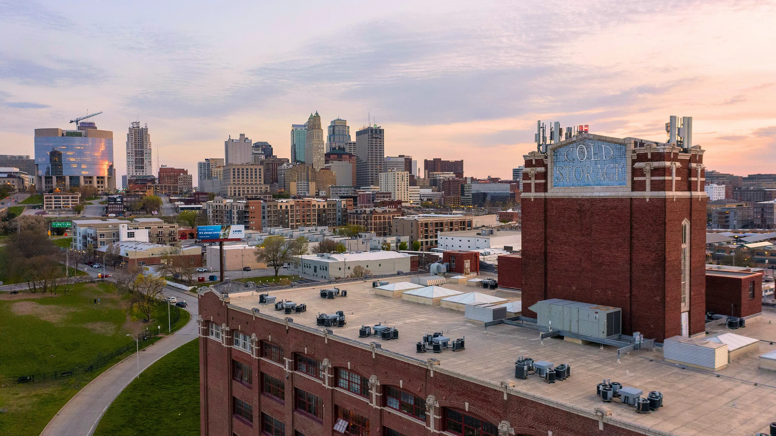 Charming urban skyline view featuring a historic brick warehouse with Cold Storage signage and a vibrant city backdrop at sunset.