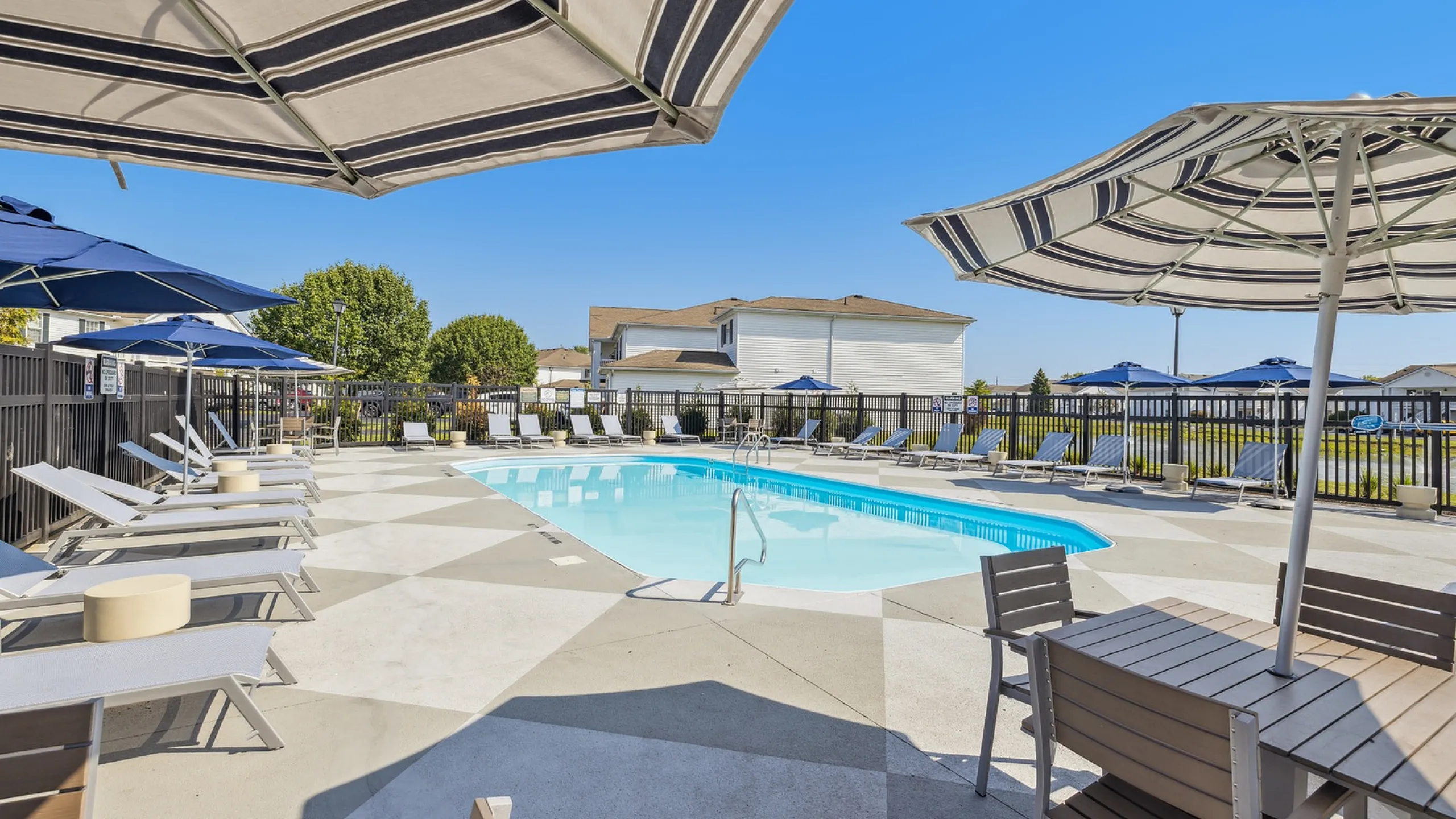 Luxurious outdoor pool area featuring stylish lounge chairs and chic umbrellas ideal for relaxation and leisure.