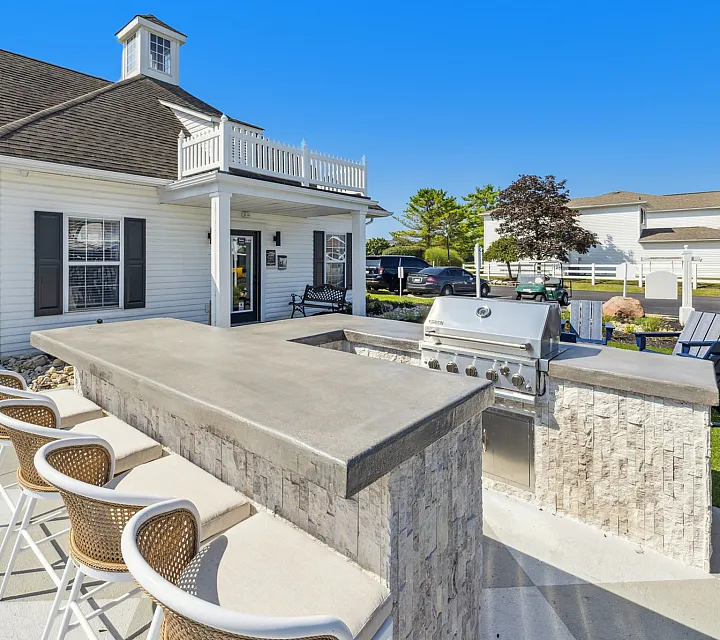 Elegant outdoor kitchen with sleek countertops and stylish bar seating at a modern apartment complex.