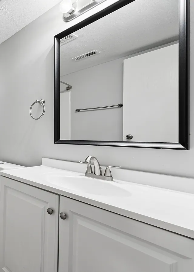 Modern bathroom with sleek fixtures, a pristine bathtub, and elegant white cabinetry.