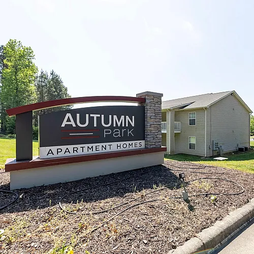 Inviting Autumn Park Apartment Homes with manicured landscaping and welcoming signage in a serene, green setting.