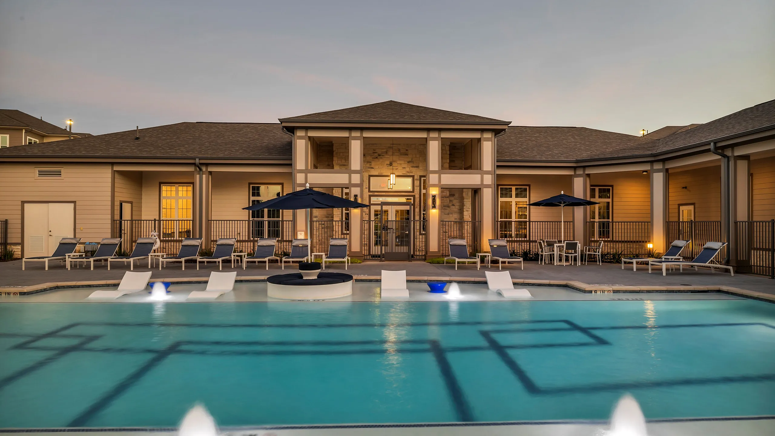 Elegant apartment complex with a luxurious pool and modern poolside seating, perfect for relaxation and leisure.