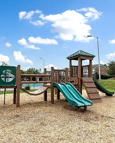 Charming community playground with slides and climbing structures under a bright blue sky, perfect for family fun.