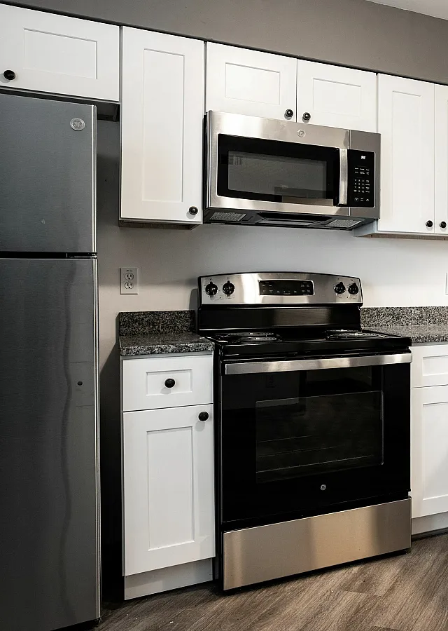 Contemporary kitchen with sleek stainless steel appliances, white cabinetry, and stylish pendant lighting.