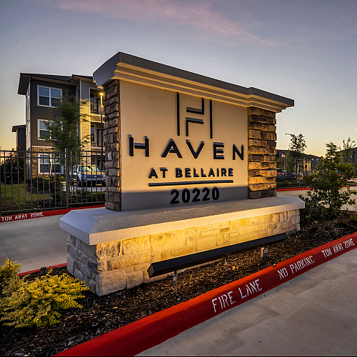 Inviting entrance to Haven at Bellaire, showcasing modern architecture and pristine landscaping at dusk.