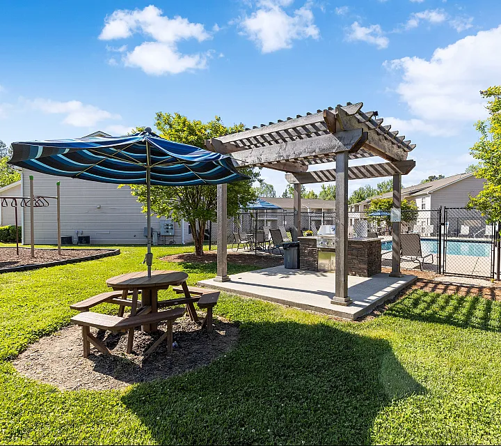 Inviting outdoor space with pergola-shaded seating, vibrant green lawn, and a sparkling pool, perfect for relaxation and social gatherings.