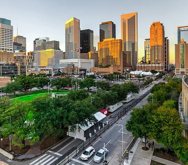 Breathtaking view of a vibrant city skyline at sunset with modern skyscrapers and lush green park.