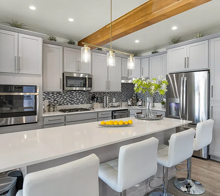 Bright and modern kitchen with sleek white cabinetry, stainless steel appliances, and a stylish breakfast bar adorned with fresh lemons and elegant lighting.